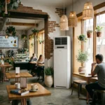 Café interior in Cyprus cooled by a floor-standing air cooler unit near a sunny window.