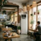 Café interior in Cyprus cooled by a floor-standing air cooler unit near a sunny window.