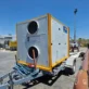 Trailer-mounted Psilos Group rooftop heat pump unit with dual fan grilles, parked outdoors on a paved yard.